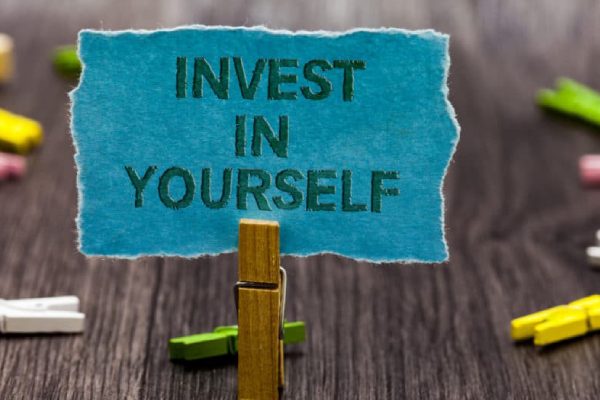 A Text Written Invest In Yourself In A Blue Paper.